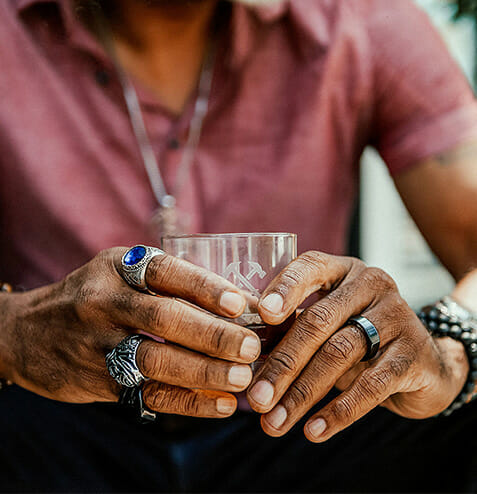 man with rings holds drink